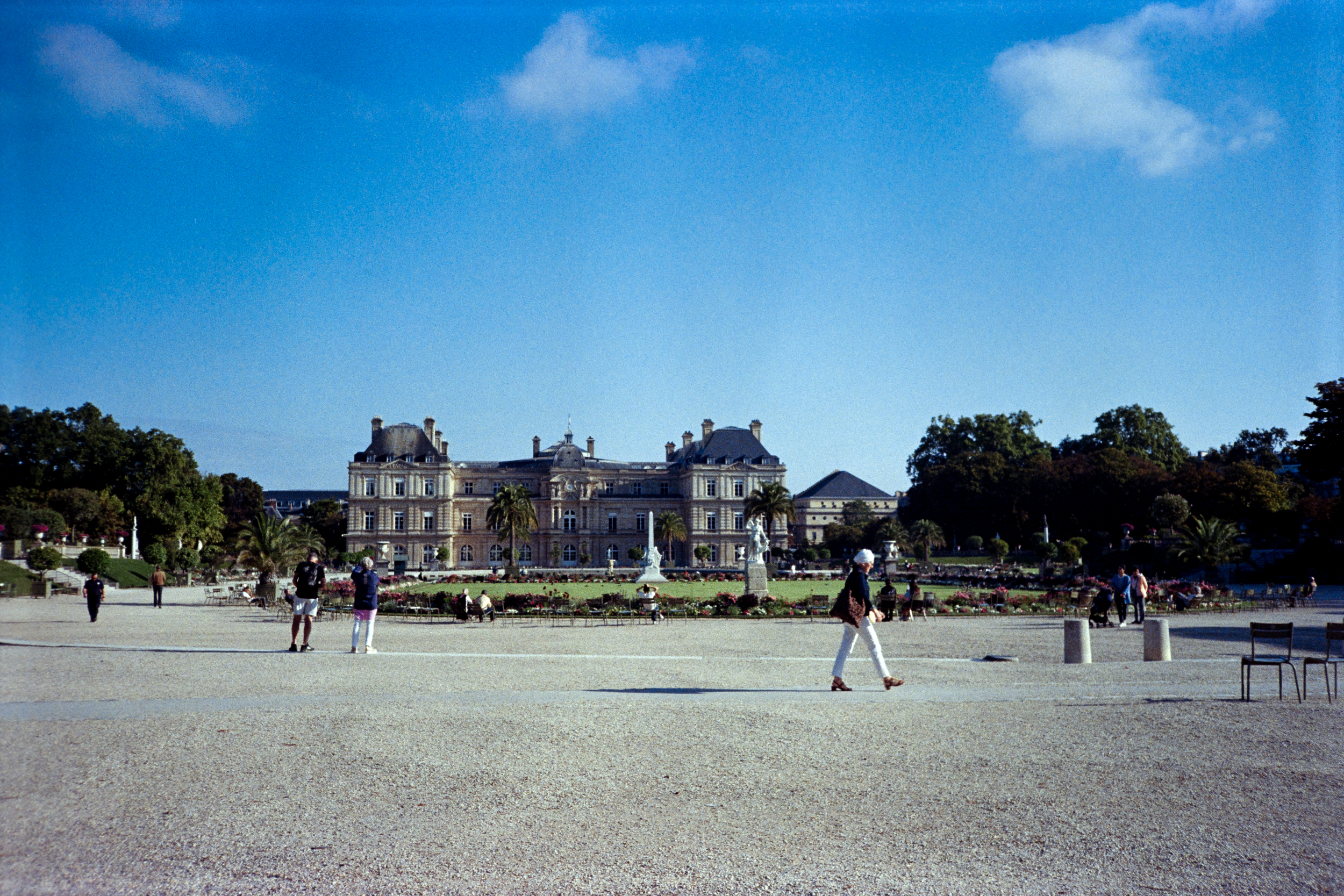 A film photo of the Jardin du Luxembourg in Paris. It is summer and there are many people walking around.